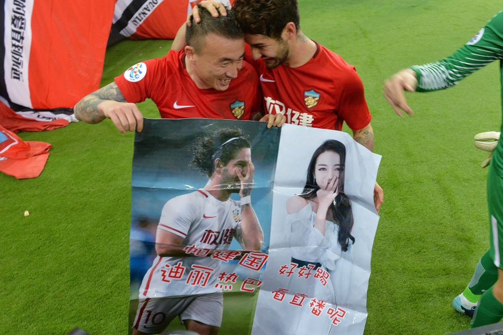 This picture taken on March 14, 2018 shows Alexandre Pato of Tianjin Quanjian (R), holding a poster showing pictures of him and Chinese actress Dilraba Dilmurat, with teammate Wang Yongpo after the AFC Champions League group stage football match between C