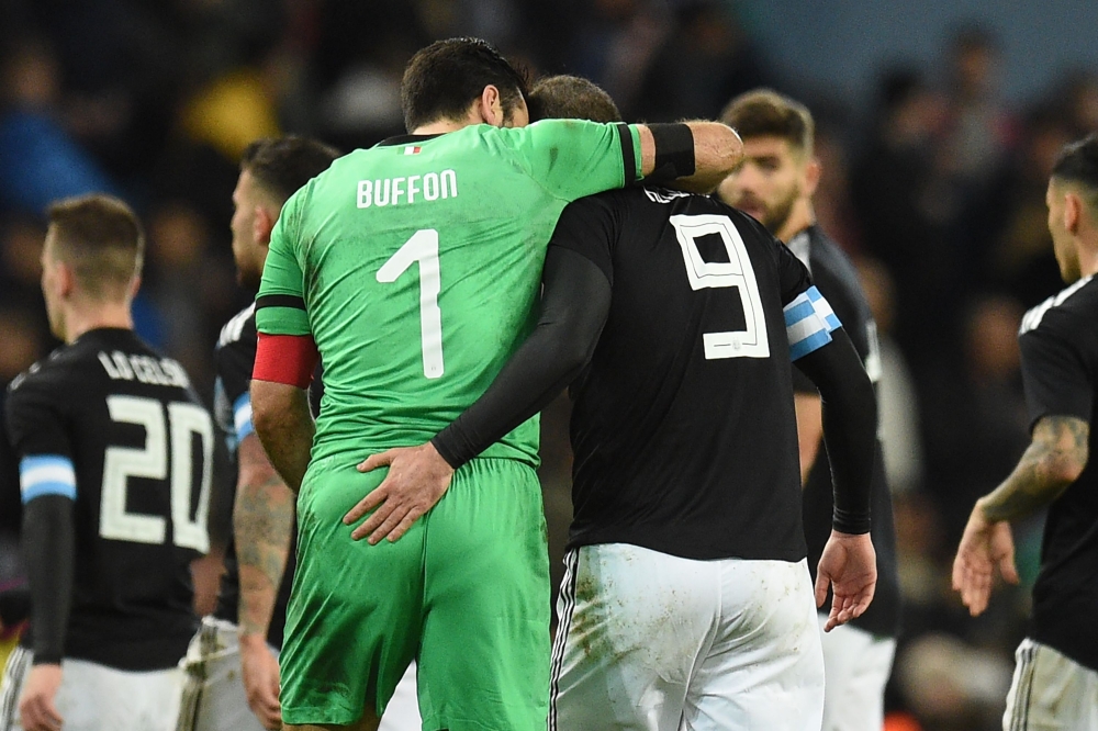 Italy's goalkeeper Gianluigi Buffon and Argentina's striker Gonzalo Higuain leave the pitch arm in arm at half time during the International friendly football match between Argentina and Italy at the Etihad stadium in Manchester, north west England on Mar