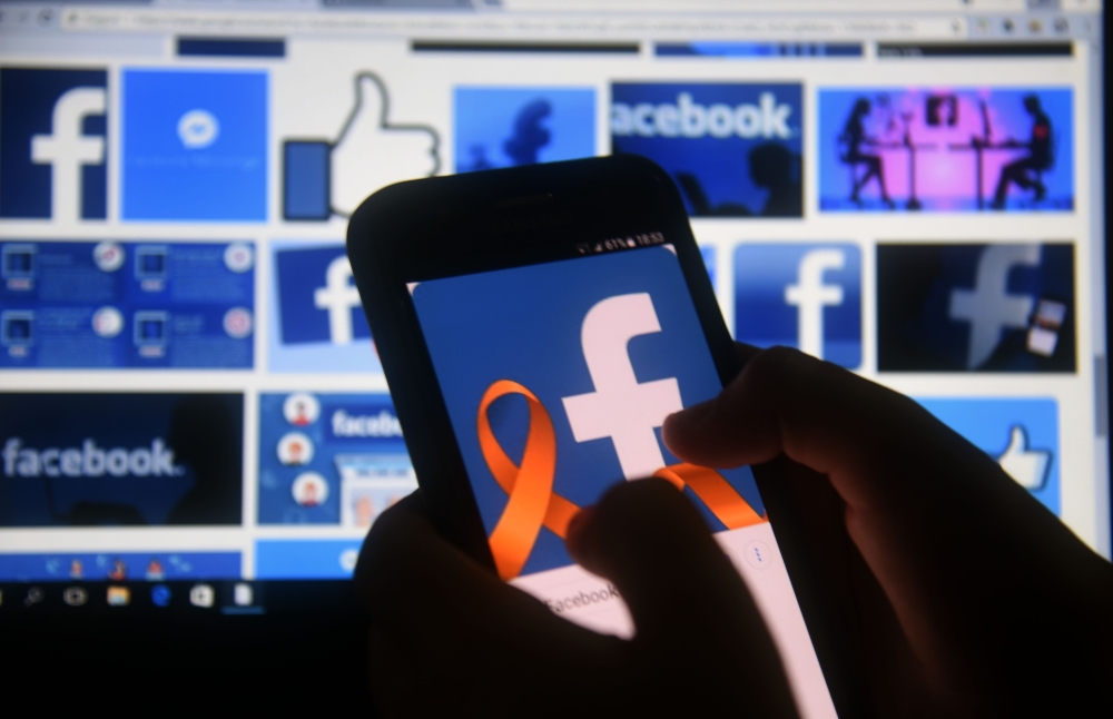 A cellphone and a computer screen display the logo of the social networking site Facebook on March 22, 2018, in Asuncion. AFP / NORBERTO DUARTE