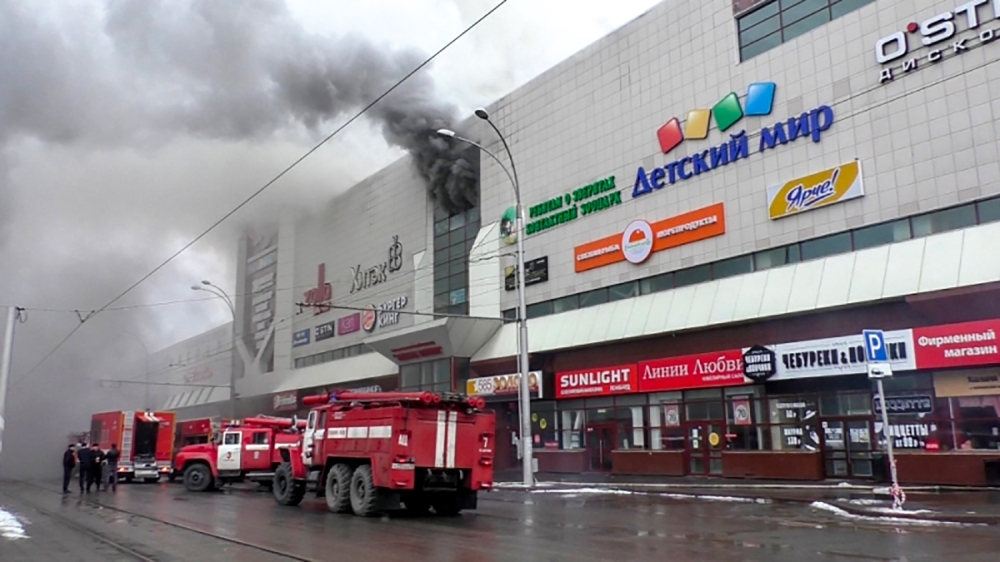 This handout picture released by The Russian Emergency Situations Ministry on March 25, 2018, shows emergency vehicles as they gather outside a burning shopping centre in Kemerovo. AFP PHOTO / RUSSIAN EMERGENCY SITUATIONS MINISTRY