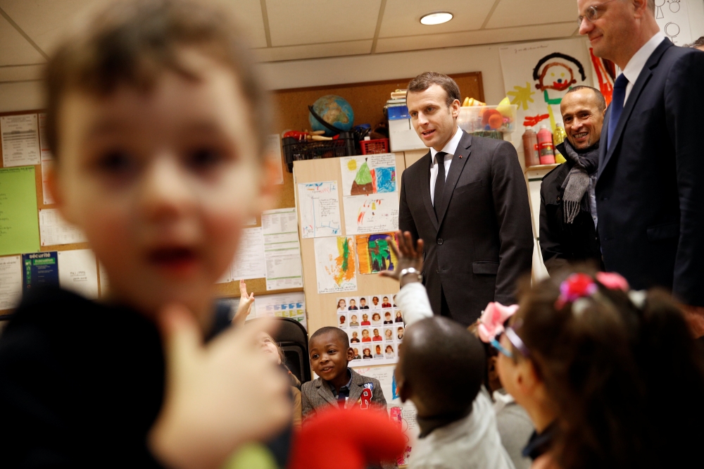 French President Emmanuel Macron (C) and French Education Minister Jean-Michel Blanquer (R) speak with pre-school children as they visit the Emelie pre-school in Paris, France, March 27, 2018. Christophe Ena/Pool via Reuters