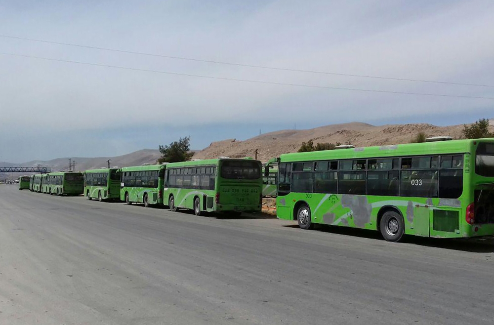 Buses waiting to take members of the opposition evacuated from the rebel-held city of Douma in the Ghouta region, at the Wafidin crossing on the outskirts of the Syrian capital Damascus on April 1, 2018.  SANA
