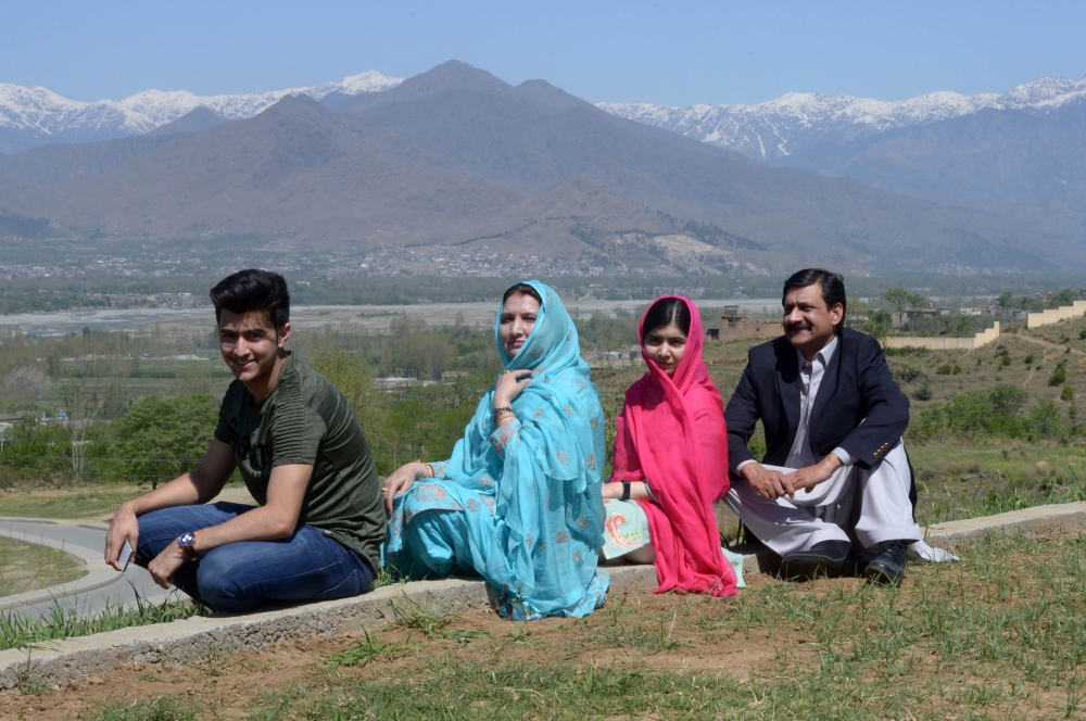 Pakistani activist and Nobel Peace Prize laureate Malala Yousafzai (2R), poses for a photograph along with her father Ziauddin Yousafzai (R), mother Torpekai (2L) and brother Atal Yousafzai (L) at the all-boys Swat Cadet College Guli Bagh, during her home