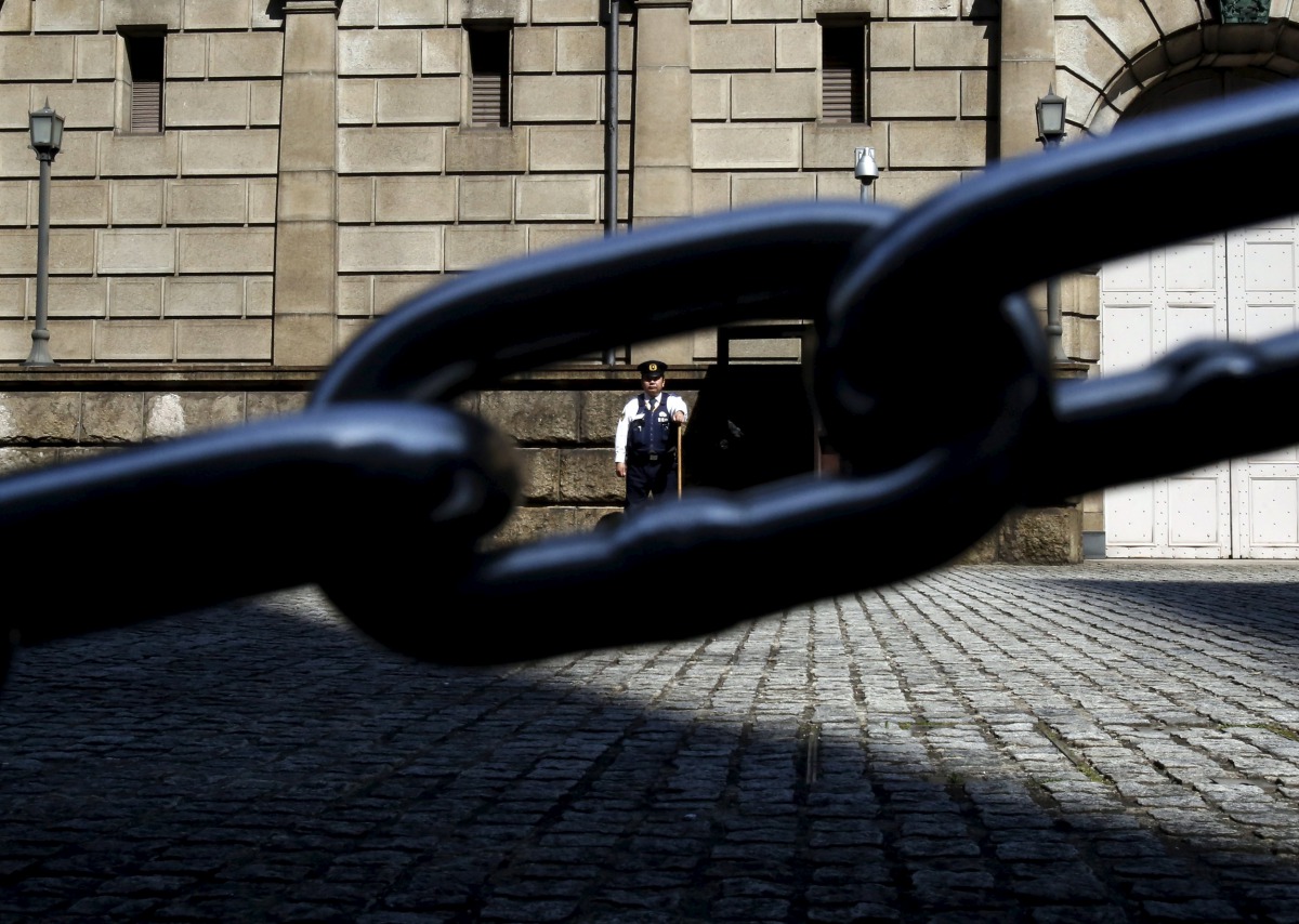 A security officer is seen through a chain link as he stands guard outside the Bank of Japan headquarters in Tokyo, March 31, 2016. Reuters / Yuya Shino