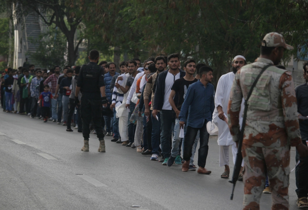 Pakistani spectators stand in a queue before entering the National Cricket Stadium to watch the third and final Twenty20 (T20) International cricket match between Pakistan and West Indies, in Karachi on April 3, 2018. / AFP / ASIF HASSAN