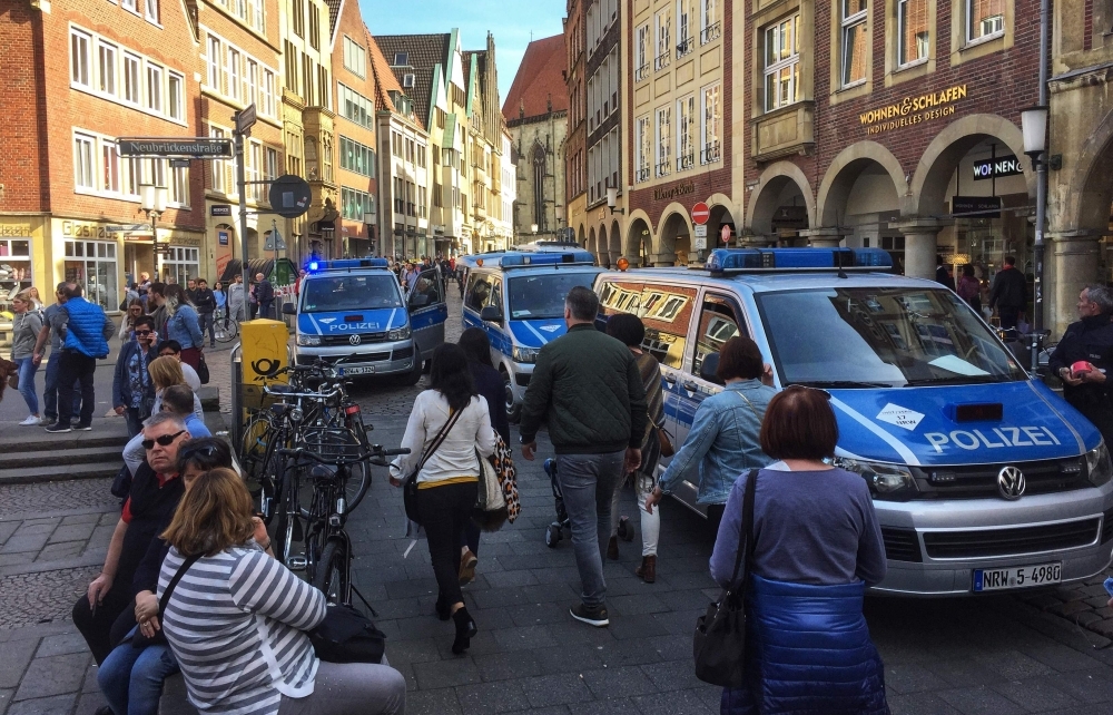 People walk past Police cars in Muenster, western Germany where several people were killed and injured when a car ploughed into pedestrians on April 7, 2018. - Germany OUT / AFP