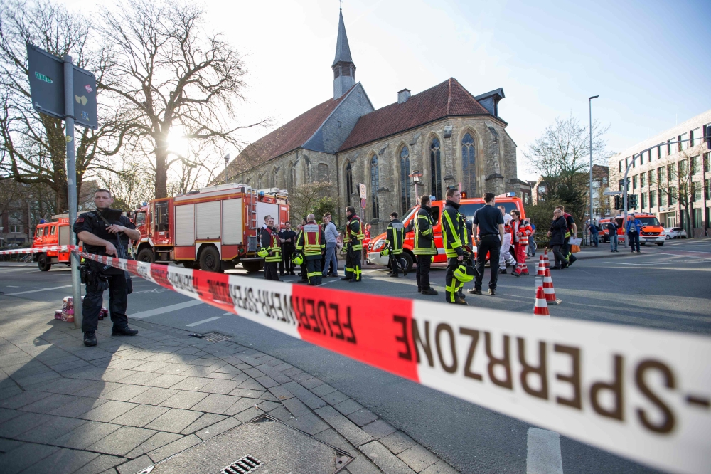An armed Police officer and first responders are seen at the scene when several people were killed and injured when a car ploughed into pedestrians in Muenster, western Germany on April 7, 2018. AFP / Friso Gentsch