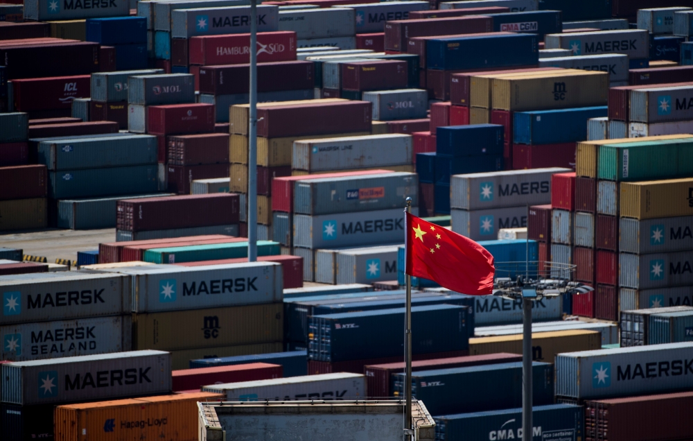 A Chinese flag is seen in front of containers at the Yangshan Deep-Water Port, an automated cargo wharf, in Shanghai on April 9, 2018.  AFP / Johannes EISELE
