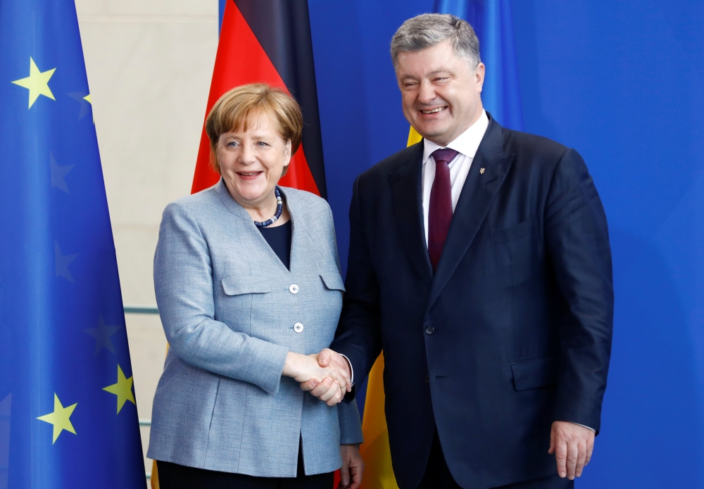 German Chancellor Angela Merkel and Ukrainian President Petro Poroshenko shake hands as they attend a news conference at the Chancellery in Berlin, Germany, April 10, 2018. REUTERS/Hannibal Hanschke
