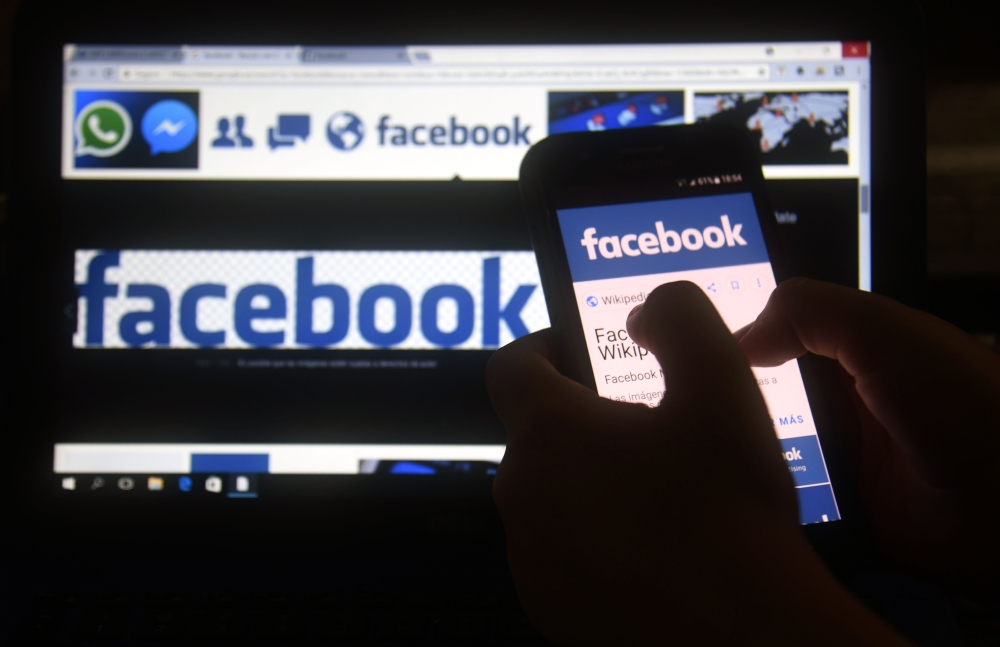 (FILES) In this file photo taken on March 22, 2018 a cellphone and a computer screen display the logo of the social networking site Facebook in Asuncion.  AFP / NORBERTO DUARTE
