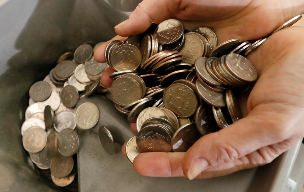 A cashier places 5 rouble coins into a counting machine at an office in Krasnoyarsk, Russia, January 22, 2016. Reuters/Ilya Naymushin