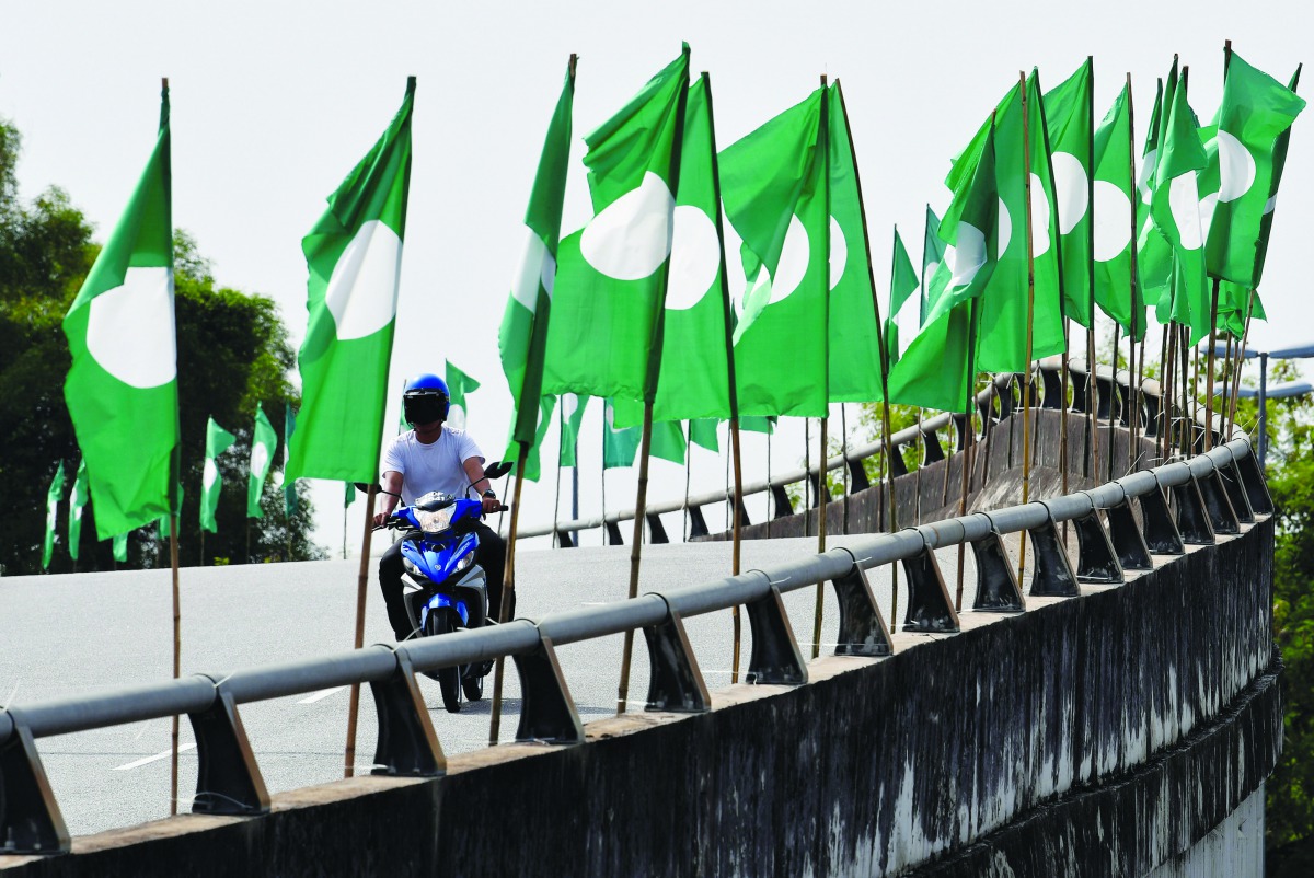 motorcyclist is seen between Parti Islam Se-Malaysia (Malaysian Islamic Party) flags in Bangi, Malaysia April 10, 2018. Reuters