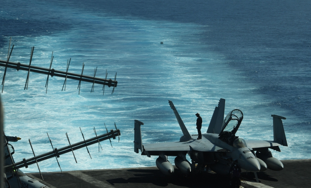 A sailor inspects atop an FA-18 hornet fighter jet during a routine training aboard US aircraft carrier Theodore Roosevelt in the South China sea on April 10, 2018. AFP / TED ALJIBE
