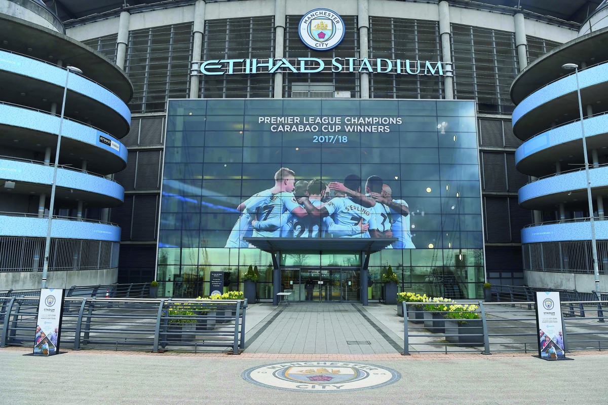 A new poster showing members of the Manchester City team celebrating has been placed at the entrance to the Etihad Stadium in Manchester, north west England to celebrate Manchester City winning the Premier League title on April 16, 2018.  AFP / Paul Ellis