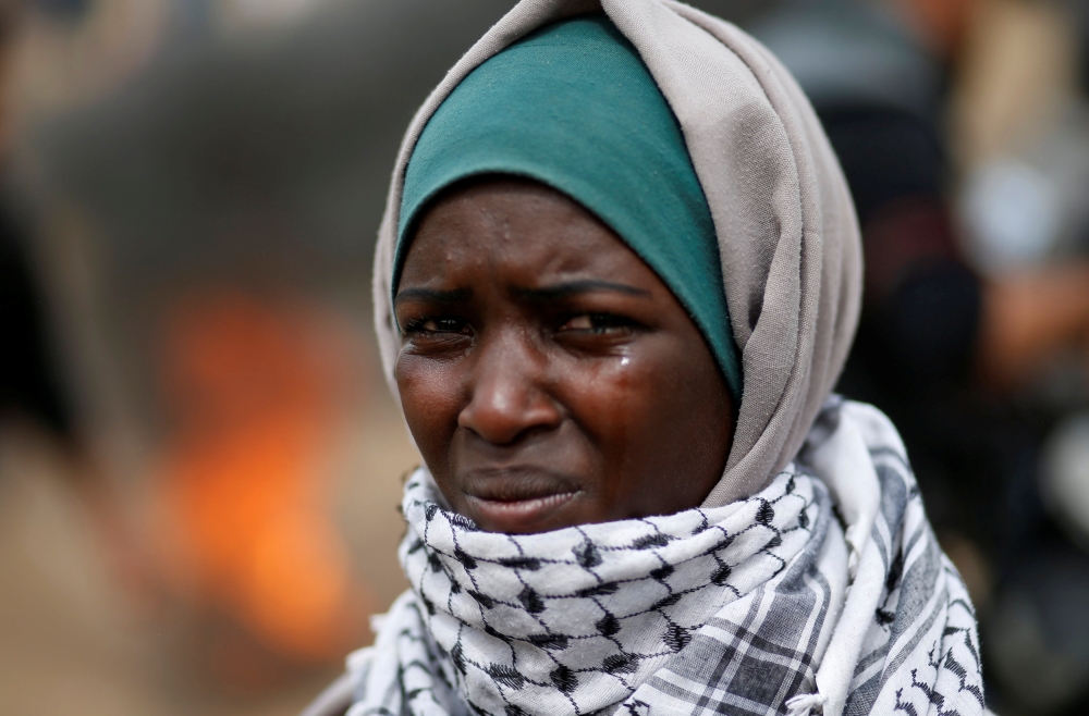 A woman demonstrator reacts to tear gas fired by Israeli troops during clashes at a protest at the Israel-Gaza border where Palestinians demand the right to return to their homeland, east of Gaza City April 20, 2018. Reuters/Mohammed Salem