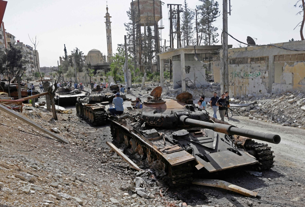 Destroyed tanks and armoured personnel carriers are pictured on a road in the Eastern Ghouta town of Douma on the outskirts of the capital Damascus on April 20, 2018, during an army-organised media tour. / AFP / LOUAI BESHARA