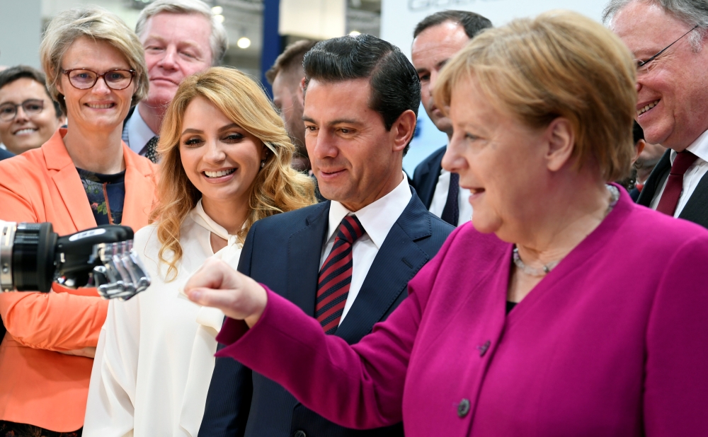 :German Chancellor Angela Merkel fist bumps with a humanoid robot as Mexican First Lady Angelica Rivera de Pena and Mexican President Enrique Pena Nieto look on, at the booth of IBG at Hannover Messe, the trade fair in Hanover, Germany, April 23, 2018. RE