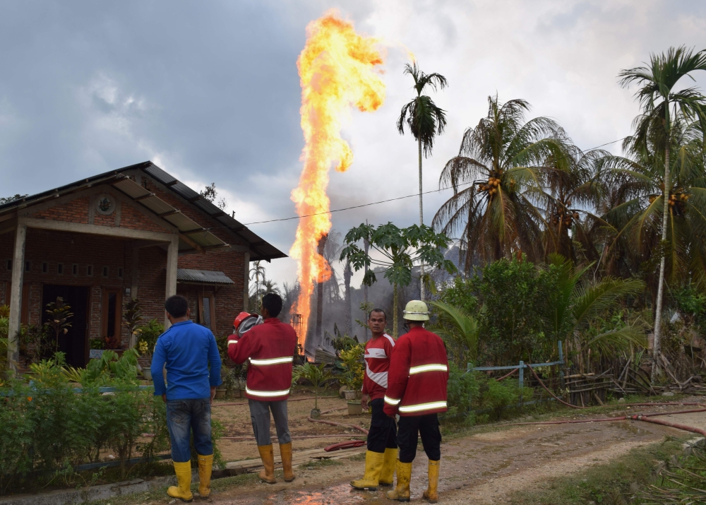 Indonesian fire fighters battle to extinguish a fire at an illegal oil well in Peureulak on April 25, 2018. At least 10 people have been killed and dozens more injured after a fire at an illegal oil well in Indonesia's Aceh province, authorities said on A