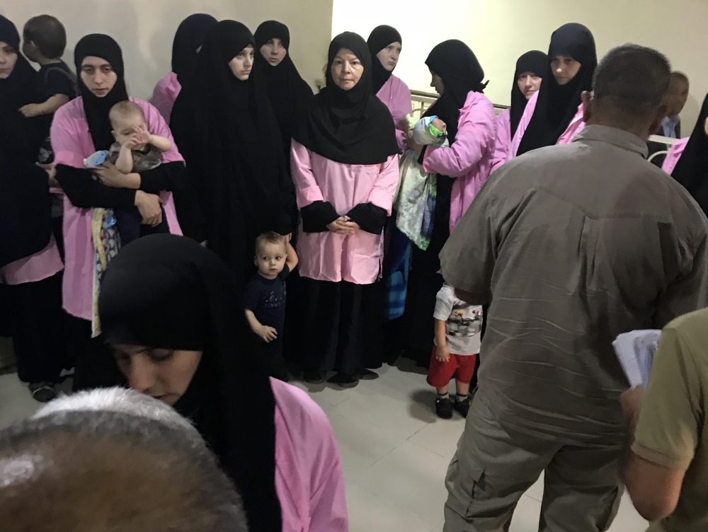 A picture taken on April 29, 2018 in the Iraqi capital Baghdad's Central Criminal Court shows Russian women who have been sentenced to life in prison on grounds of joining the Islamic State (IS) group standing with children in a hallway. Iraq sentenced 19
