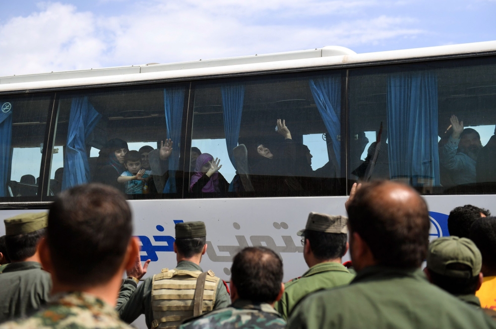 Syrian civilians from the area of Ishtabraq, where they had been held hostage since 2015, arrive on buses after being evacuated from the rebel area to the al-Eis checkpoint in Aleppo province on May 1, 2018. AFP / George Ourfalian 