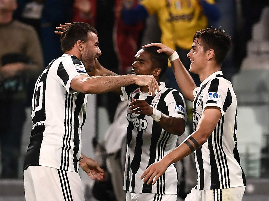Juventus' forward Paulo Dybala from Argentina celebrates with teammate Juventus' midfielder Douglas Costa from Brazil (C) and Juventus' defender Andrea Barzagli (L) after scoring a goal during the Italian Serie A football match between Juventus and Bologn