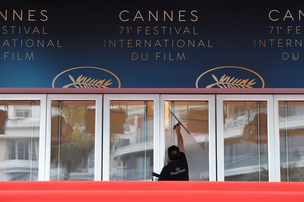 A staff member cleans the doors of the festival's palace on May 8, 2018 ahead of the opening of the 71st edition of the Cannes Film Festival in Cannes, southern France. / AFP / LOIC VENANCE