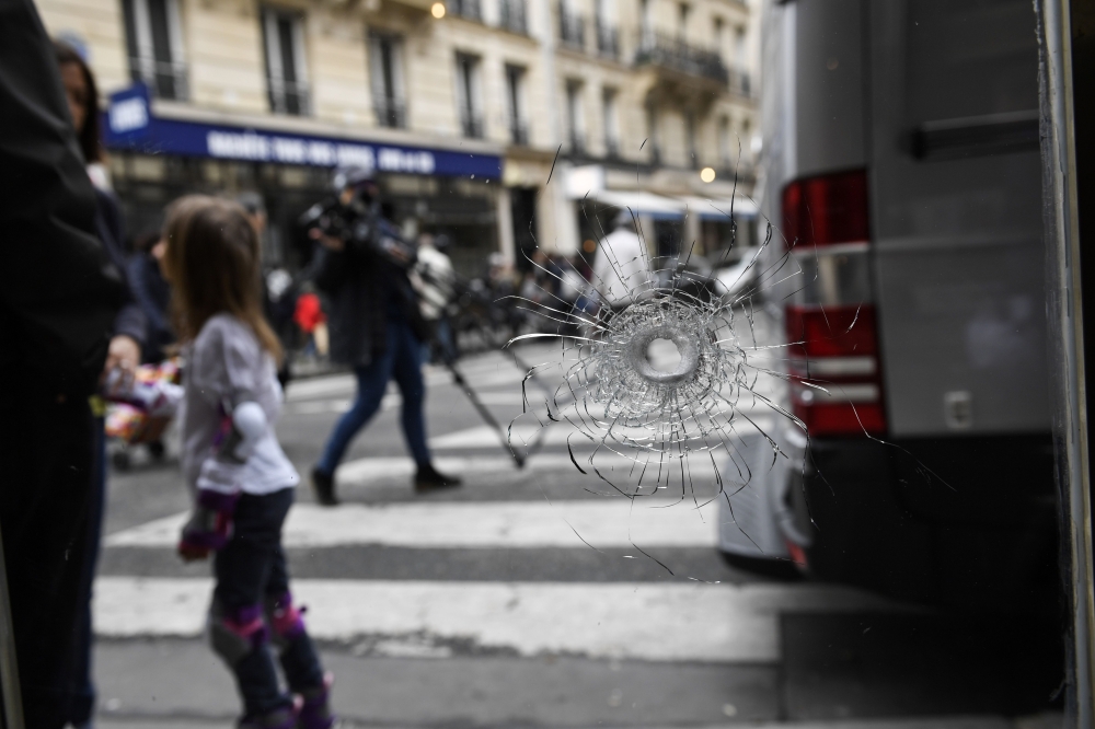 A bullet hole, seen on the window of a cafe located at the crossroads between the streets Saint-Augustin and Monsigny, is pictured on May 13, 2018 in Paris, the day after a knifeman killed one man and wounded four other people.  AFP / Eric FEFERBERG
