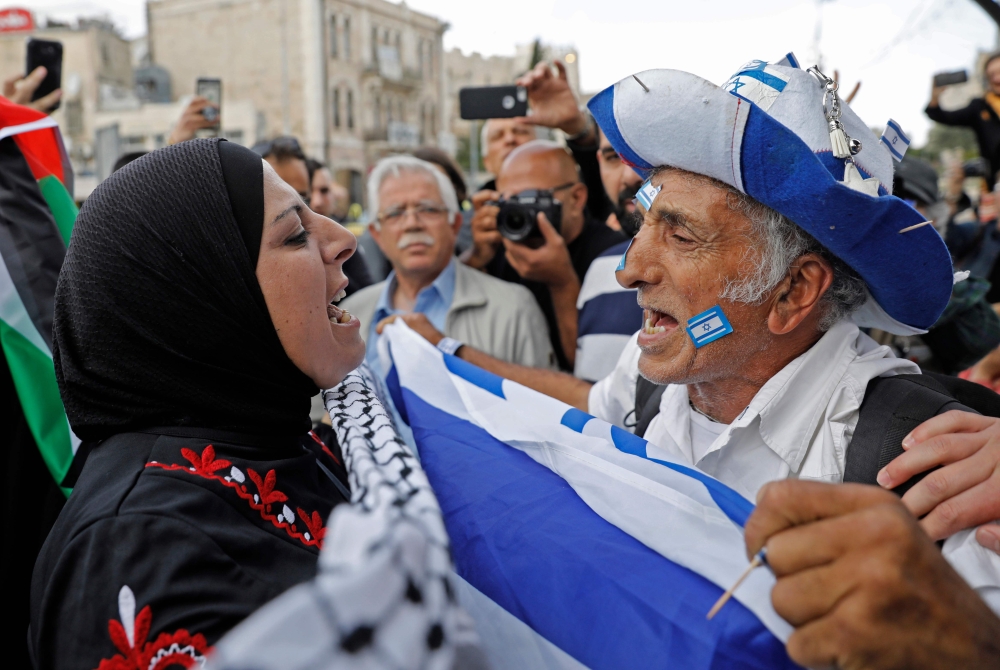 An Israeli man confronts a Palestinian woman at Damascus gate in Jerusalem on May 13, 2018, as Israeli nationalist settlers celebrate the Jerusalem Day in the Old City.  AFP / Menahem Kahana