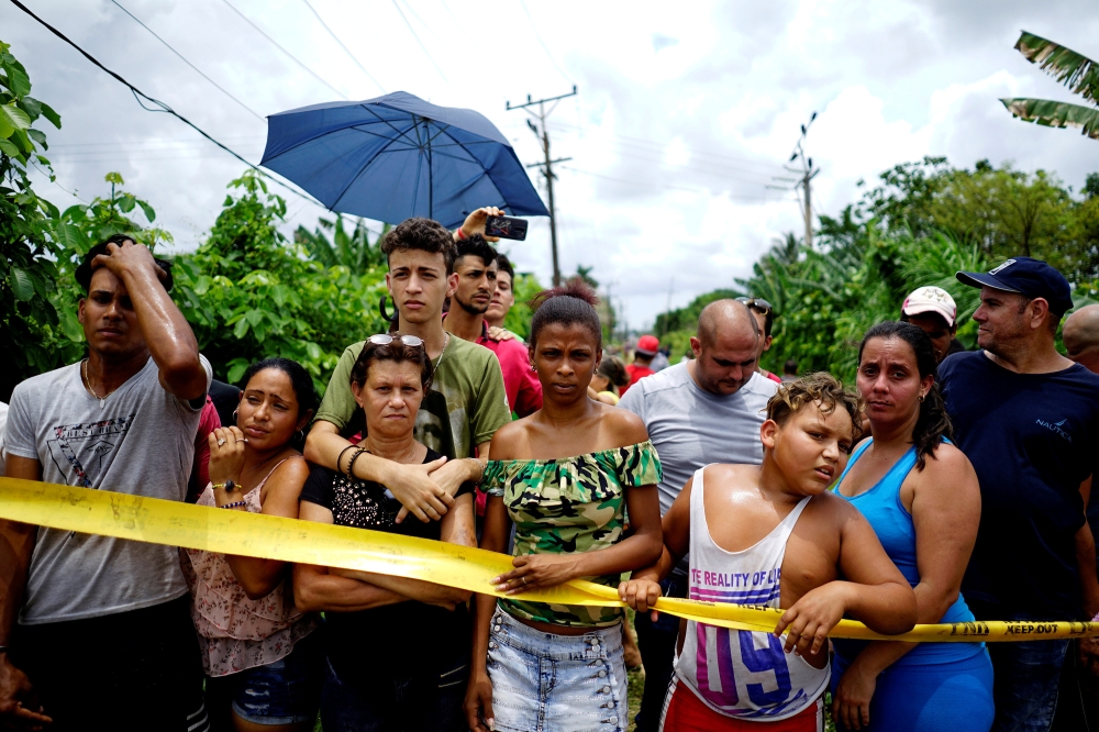 People look on near of the wreckage of a Boeing 737 plane that crashed in the agricultural area in Boyeros, around 20 km (12 miles) south of Havana, on Friday shortly after taking off from Havana's main airport in Cuba, May 18, 2018. Reuters/Alexandre Men