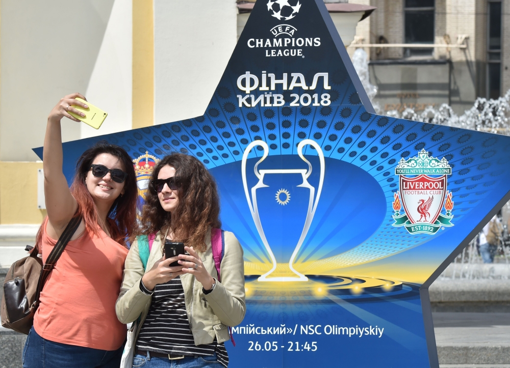 Girls make selfie in front of the official logo set on the Independence Square in the Ukrainian capital of Kiev on May 22, 2018, ahead of 2018 UEFA Champions League Final football match between Real Madrid and Liverpool FC next May 26 at the Olimpiyskiy S