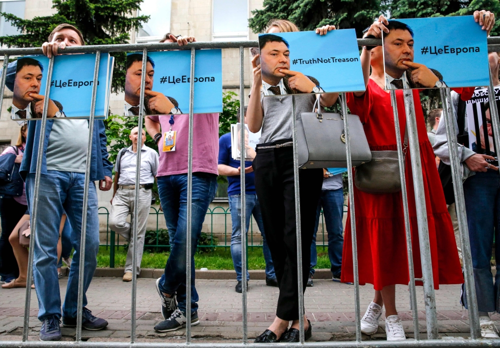 People hold pictures of journalist from Russia's state-run RIA Novosti news agency Kirill Vyshynsky as they protest against his arrest in front of the Ukrainian embassy in Moscow on May 18, 2018.  AFP / Maxim ZMEYEV
