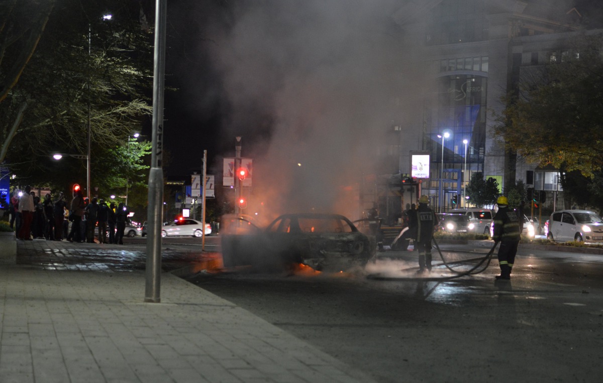 File photo: Firefighters extinguish a car that police said was set on fire during a confrontation between Uber and meter taxi drivers in Sandton, South Africa, September 7, 2017. (Reuters / Sipho Sithole) 