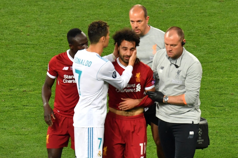 Liverpool's Egyptian forward Mohamed Salah (C) is comforted by team members and Real Madrid's Portuguese forward Cristiano Ronaldo (2nd L) as he leaves the pitch after injury during the UEFA Champions League final football match between Liverpool and Real