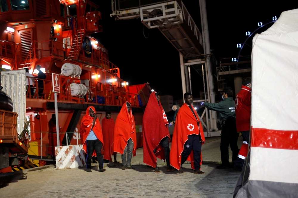 Migrants, part of a group intercepted aboard two dinghies off the coast in the Mediterranean Sea, enter a tent of the Spanish Red Cross after arriving on a rescue boat at the port of Malaga, Spain May 22, 2018. Picture taken May 22, 2018. REUTERS/Jon Nazc