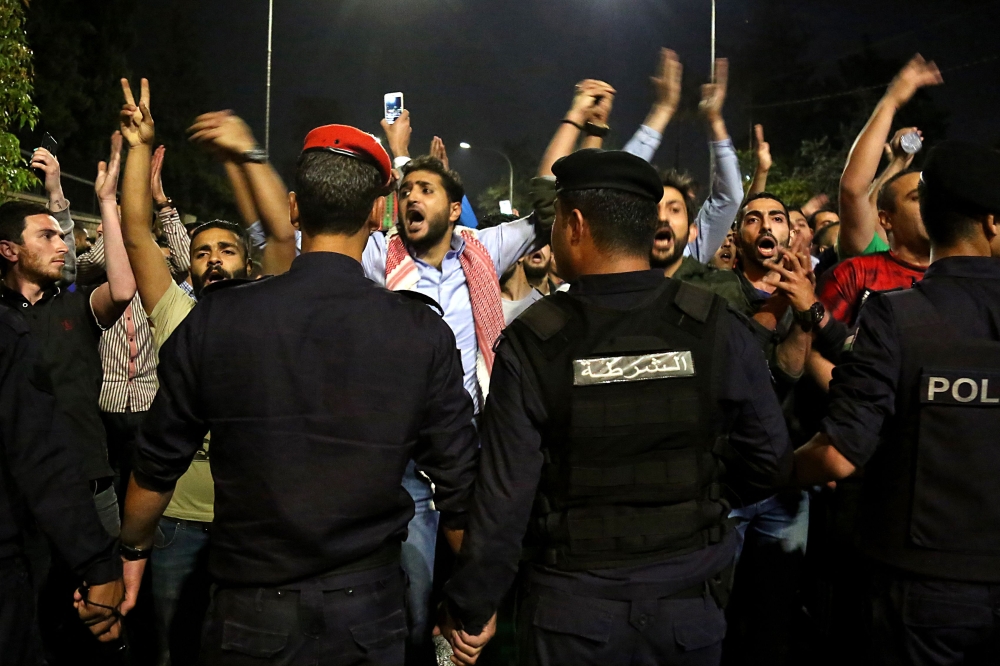 Demonstrators confront anti-riot policemen as they protest against against a proposed income tax draft law in front of the Prime Minister's office in Amman, late on June 1, 2018.   AFP / STRINGER
