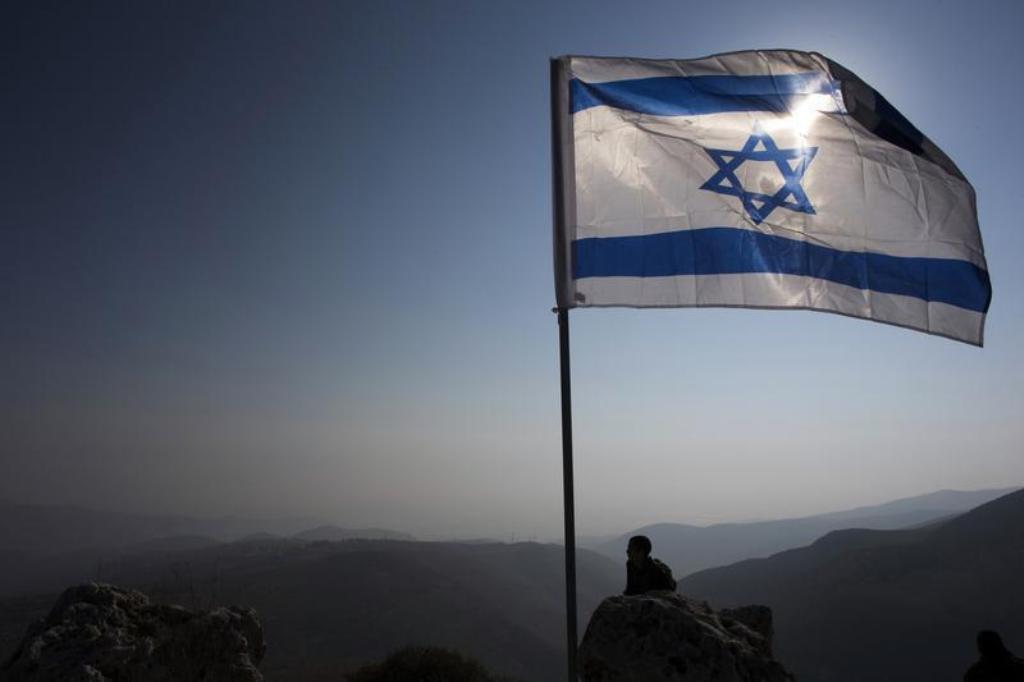 File photo of an Israeli soldier standing guard under an Israeli national flag during a tour made by Israeli parliament members in the Jordan Valley near the Jewish settlement of Maale Efrayim January 2, 2014. Credit: Reuters/Ronen Zvulun