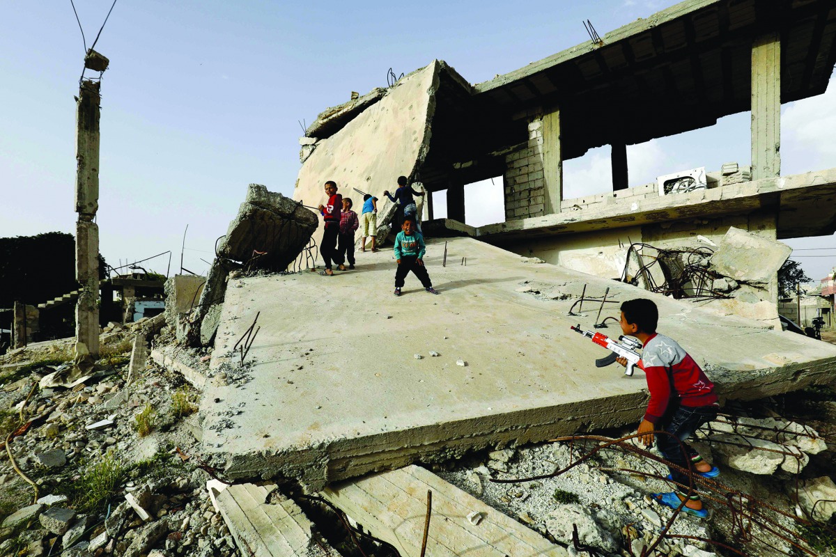 Syrian children play among destroyed buildings in Kobane on May 27, 2018.  AFP / Delil souleiman