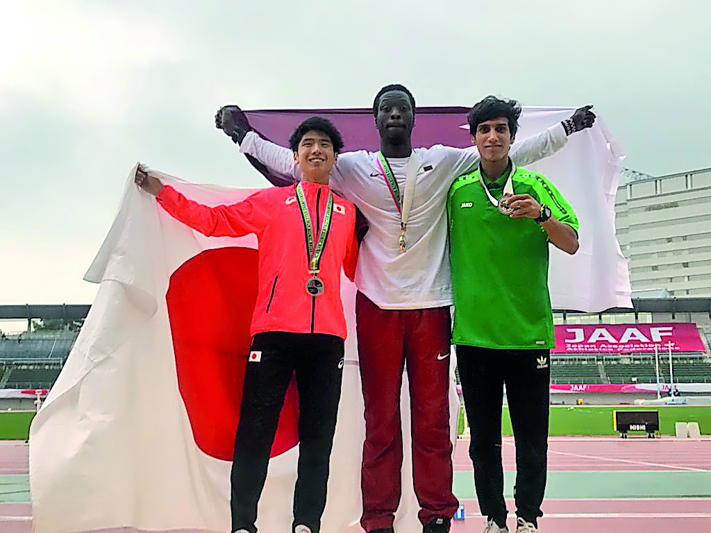 Qatar’s Muhand Saifeldin (B), winner of two gold medals  in 1,500m and 3,000m steeplechase celebrates on the podium.  
