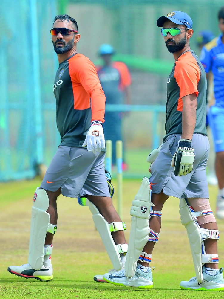 Indian test cricket team captain Ajinkya Rahane (R) and wicket keeper Dinesh Karthik walk together during the team's practice session at the M. Chinnaswamy Stadium in Bangalore on June 13, 2018, on the eve of their one off test match against Afghanistan. 