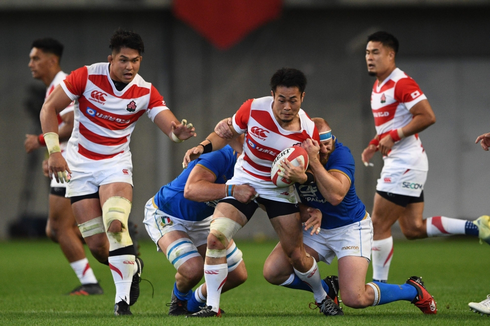 Japan's winger Kenki Fukuoka (C) is tackled during the rugby union Test match between Japan and Italy at Noevir Stadium in Kobe on June 16, 2018. / AFP / Martin BUREAU