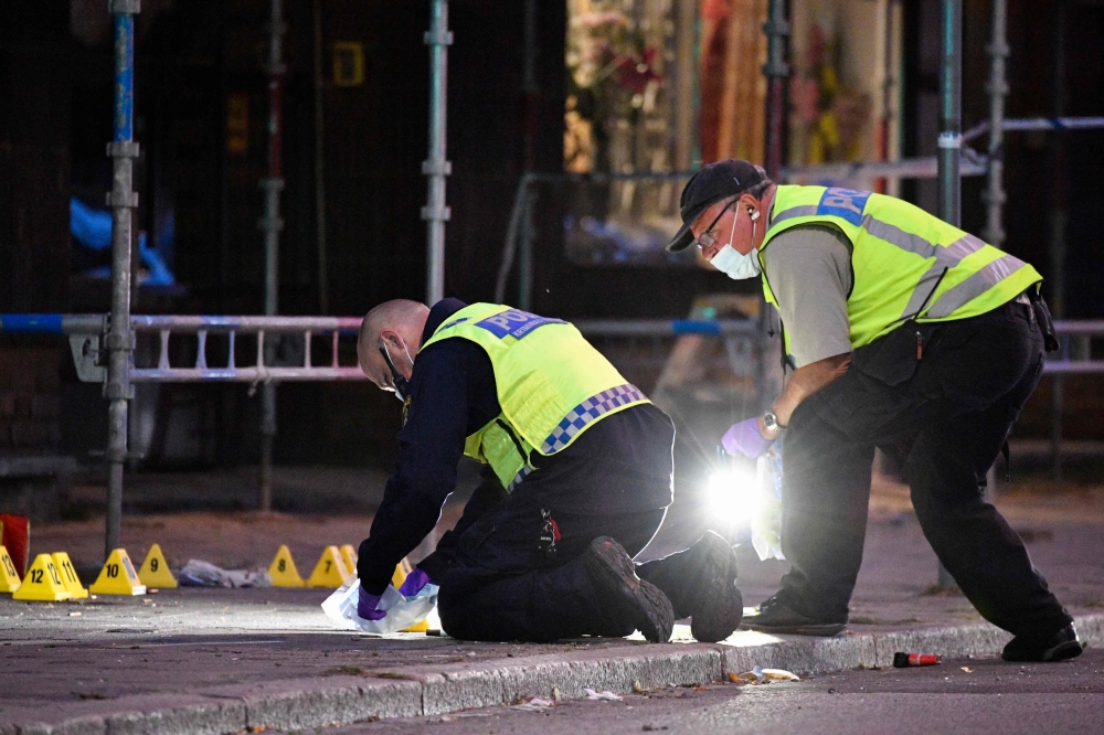 Policemen search the scene after five people were hurt in a shooting in the centre of the southern Swedish city of Malmo on June 18, 2018.  AFP / Johan NILSSON