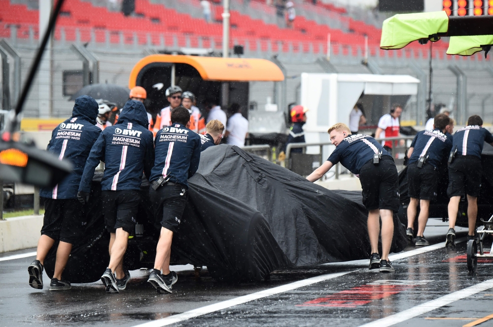Technicians put rain covers over the cars of Force India's drivers during a heavy rain shower during the third practice session at the Circuit Paul Ricard in Le Castellet, southern France, on June 23, 2018, ahead of the Formula One Grand Prix de France. A