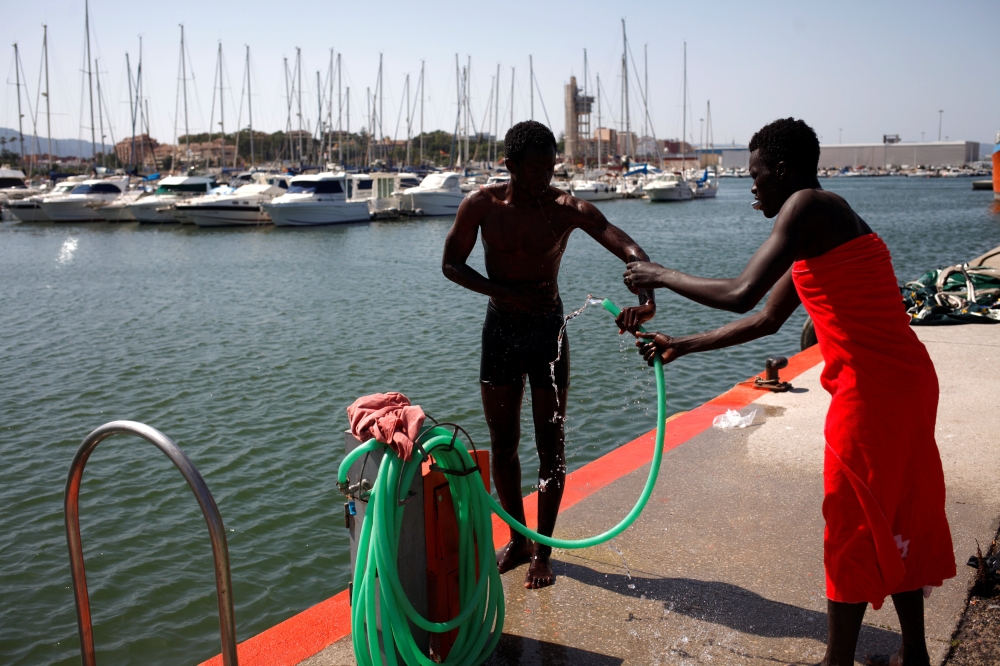 Migrants, part of a group intercepted aboard dinghies off the coast in the Strait of Gibraltar, wash themselves after arriving on a rescue boat at the port of Algeciras, southern Spain, June 26, 2018. REUTERS/Jon Nazca
