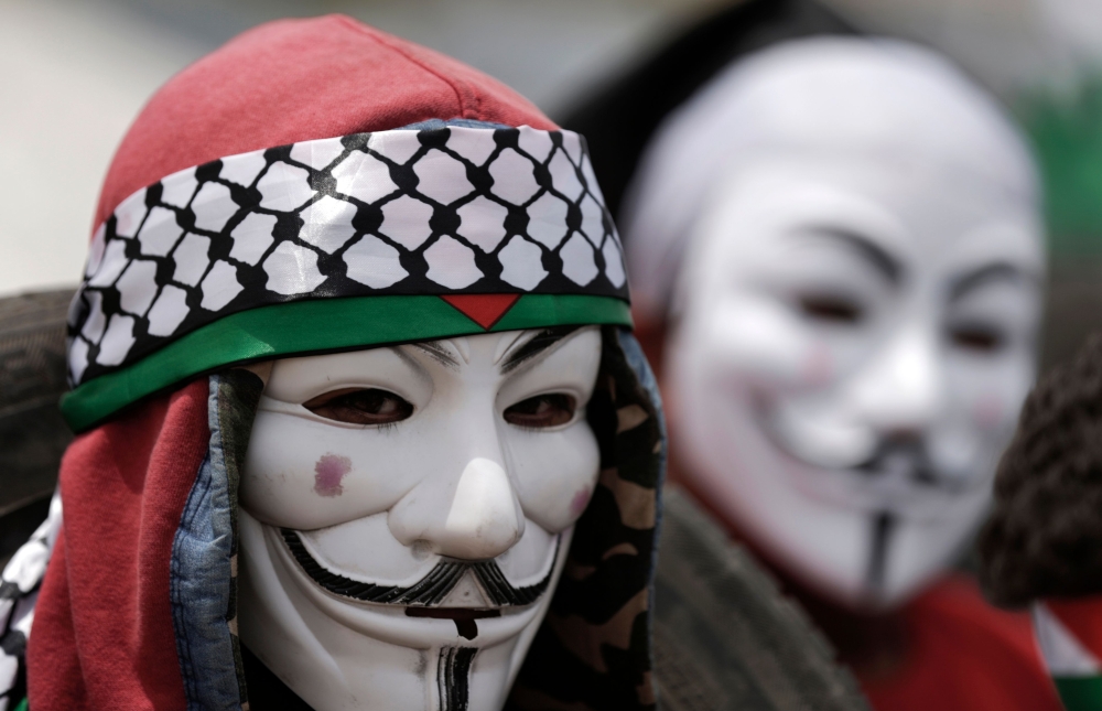 A Palestinian demonstrator wearing an Anonymous mask protests on the Israel-Gaza border, east of Gaza City in the central Gaza Strip on April 27, 2018. (AFP / Mahmud Hams) 