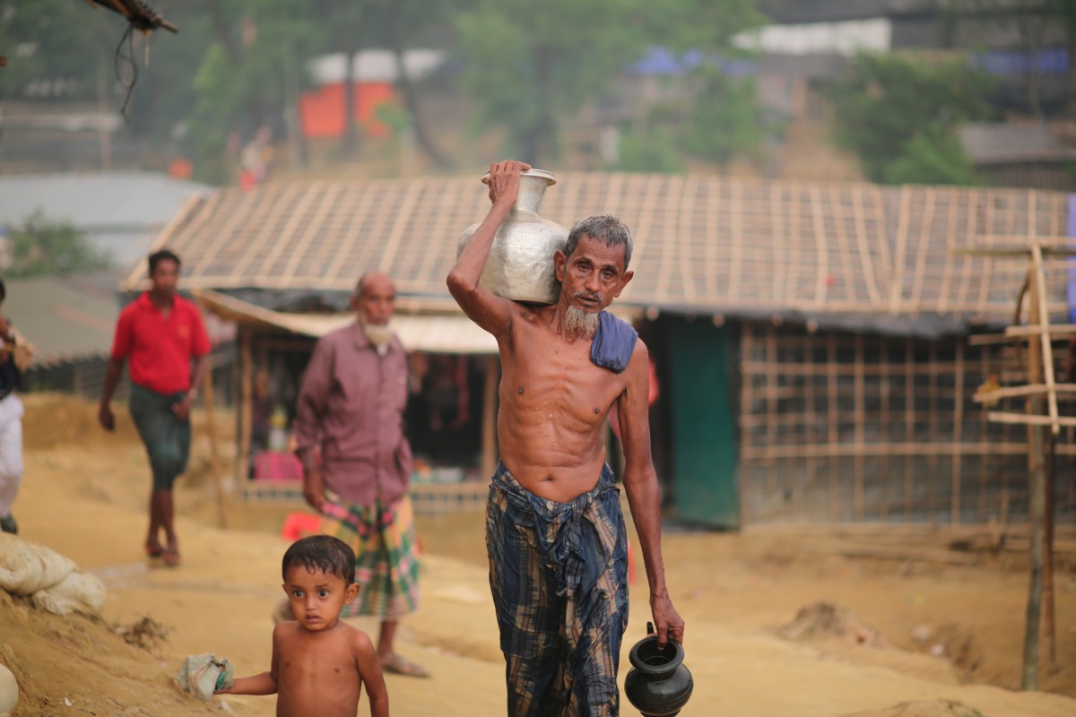 A Rohingya man walks through the mud along with a kid as they take shelter at a makeshift camp in Coxs' Bazar, Bangladesh on September 24, 2017. (Zakir Hossain Chowdhury / Anadolu Agency) 