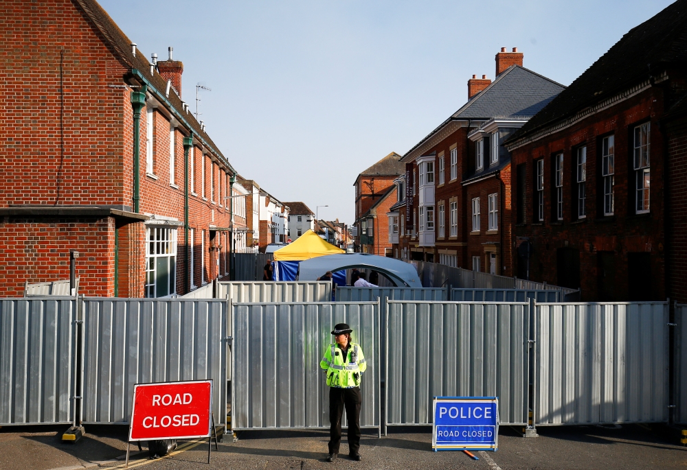 A police officer stands in front of screening erected behind John Baker House, after it was confirmed that two people had been poisoned with the nerve-agent Novichok, in Amesbury, Britain, July 5, 2018. (REUTERS/Henry Nicholls/File Photo)