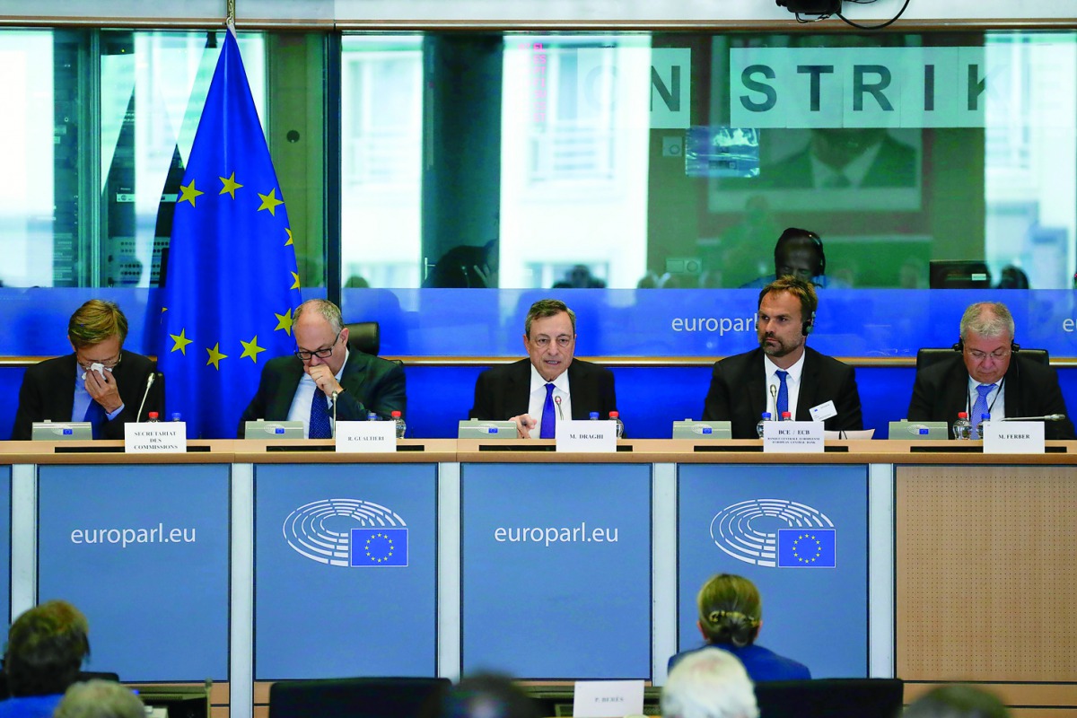 European Central Bank (ECB) President Mario Draghi (C) delivers a speech during a meeting of the Committee on economic and monetary affairs (ECON) at the European Parliament, in Brussels, on July 9, 2018, in front of signs reading 