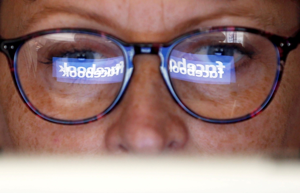 FILE PHOTO: The Facebook logo is reflected on a woman's glasses in this photo illustration taken June 3, 2018. REUTERS/Regis Duvignau/Illustration/File photo