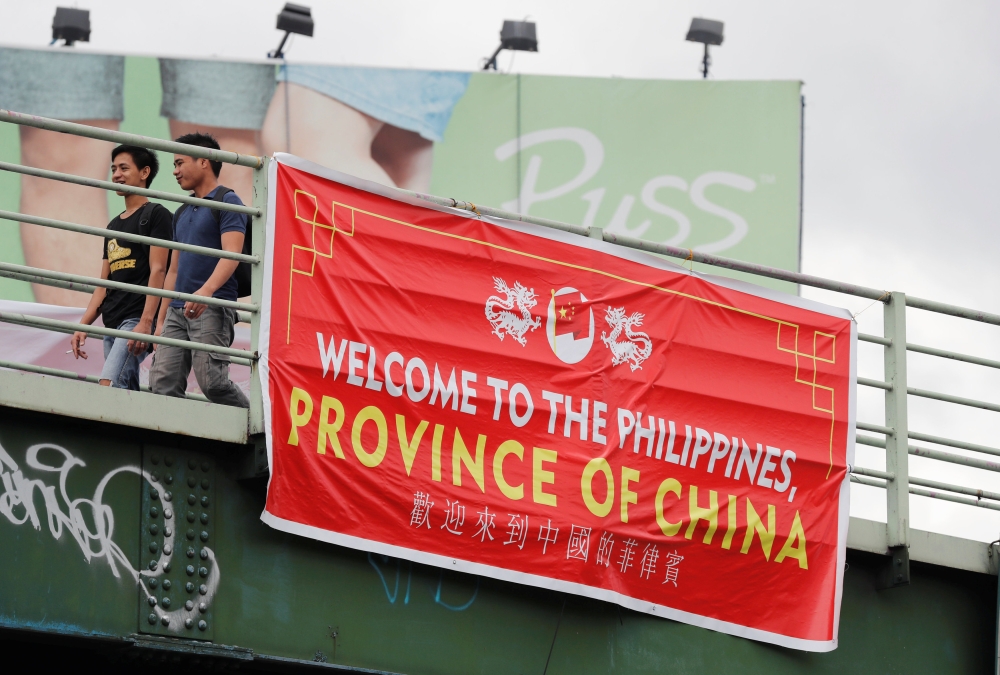 Residents walk past a banner reading 