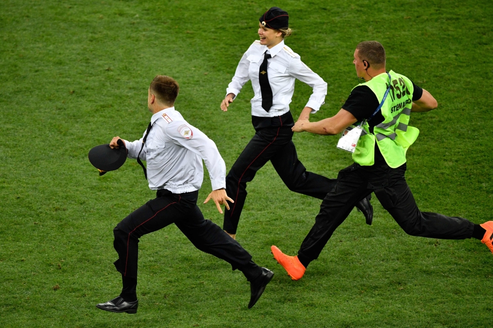 Member of security runs after strikers on the football pitch during the Russia 2018 World Cup final football match between France and Croatia at the Luzhniki Stadium in Moscow on July 15, 2018. AFP / Alexander Nemenov

